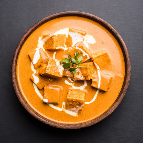 Brindavan Cafe's paneer butter masala, a rich orange curry with paneer cubes, cream swirls, and cilantro.
