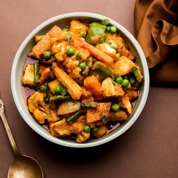 A vibrant bowl of Indian mixed vegetable curry with paneer, peas, carrots, and cauliflower.