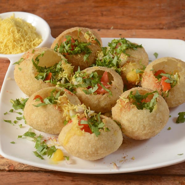 A plate of Brindavan Cafe's pani puri, filled with vegetables and topped with sev and cilantro.